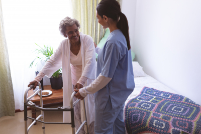 female nurse helping out a senior female patient to stand on walker