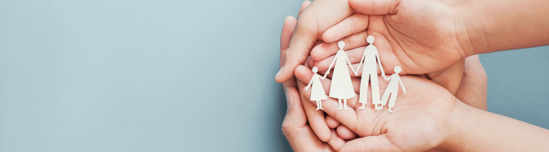 Child and adult hands holding a paper family